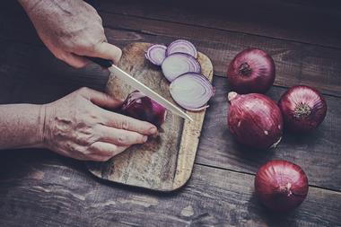 Chopping onions on a wooden board with a ceramic knife
