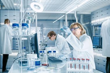 Researchers in a lab, observing blue liquid in a beaker