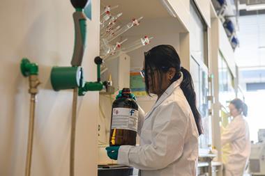 A photograph of a woman wearing PPE handling DCM in a laboratory