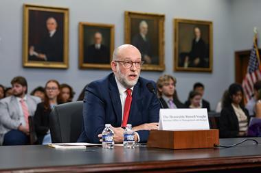 The Honorable Russell Vought, Director of the Office of Management and Budget speaks in front of a committee. Behind him is an audience with old portrait on the wall.