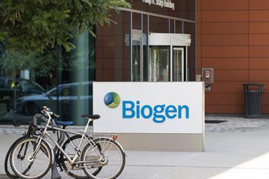 A sign saying Biogen with bikes locked nearby outside a modern office building