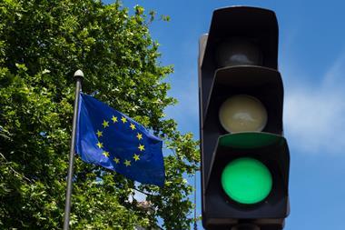 A green traffic light next to an EU flag