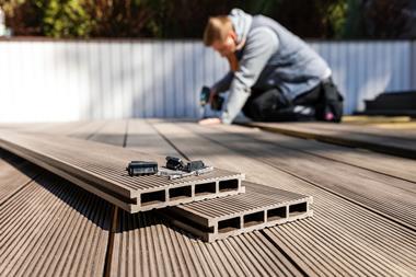 A man constructing a garden decking area using planks made of a composite materia