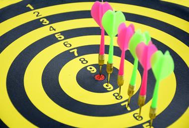 A yellow and black dartboard with darts in each ring, cumulating in a bullseye