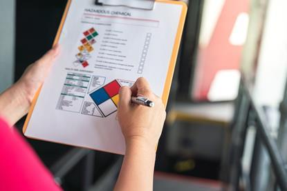 Someone fills in a hazardous chemical safety checklist on a clipboard