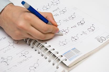 Hand writing organic chemistry structures in ballpoint pen on a notebook