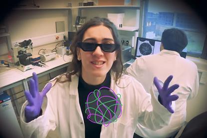 A woman in a laboratory wearing sunglasses, latex gloves and a white coat rapping about DNA