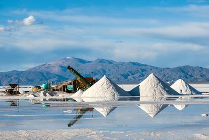 A working lithium mine with piles of salt and a view of the Andes mountain range behind
