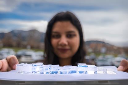 A researcher holds a tray of different sized blocks of Mochi - a thermally insulating transparent polymer