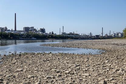 Low water levels in the Rhine river, with Evonik chemical plant in the background
