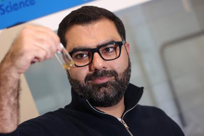 Dr. Mehrdad Zare looking at a yellow liquid in a vial