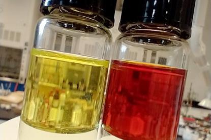 Two glass vials one contains a yellow liquid and the other contains a reddish brown liquid