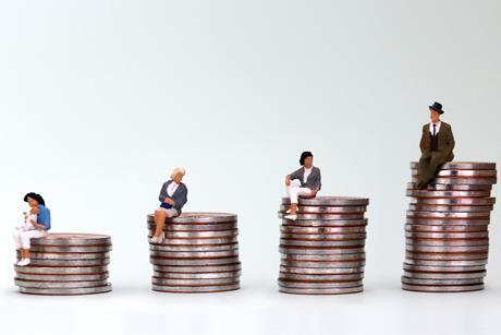 Models of tiny people sitting on stacks of coins. A man is on the tallest stack and a mother and baby is on the smallest with two other woman in between.