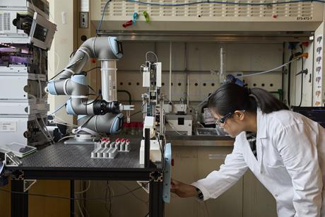 Scientist operating robotic arm in lab