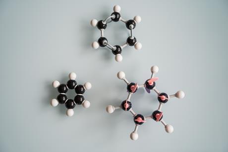 Three benzene ball and stick models arranged on a grey background