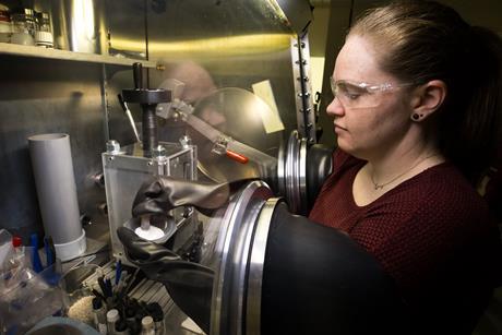 A scientist working with raw materials in a controlled environment