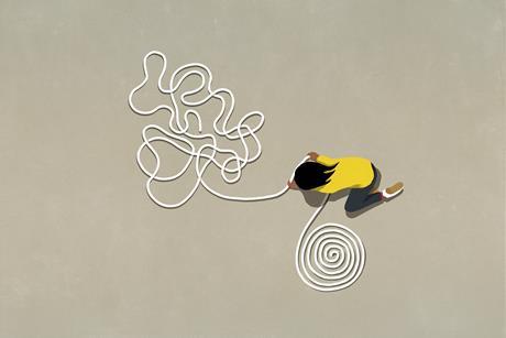 A person with long dark hair wearing a yellow top transforms a tangled coil of white rope into a neat spiral