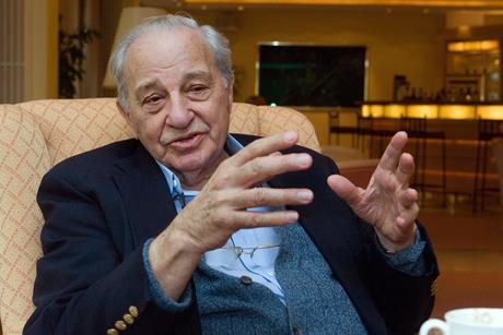 Rudolph Marcus sitting in an armchair gesturing with his hands as he speaks