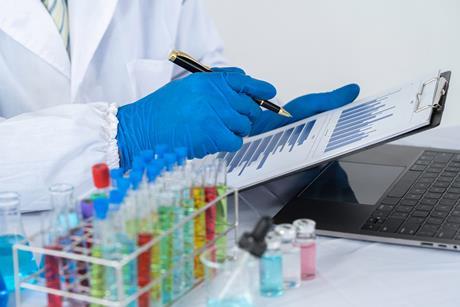 Photo of a chemist sitting at a lab bench looking at data in front of their computer