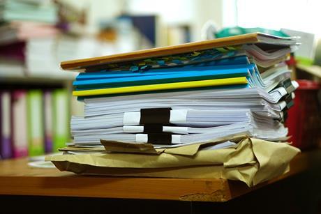A stack of papers and books on a desk in an office