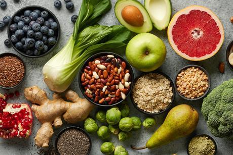 Looking down on a colourful assortment of fruit, nuts and vegetables on a grey marble worktop