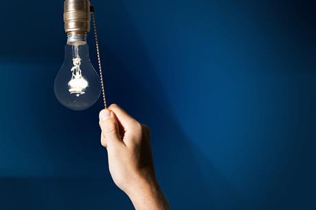 A hand turning off a lightbulb by pulling a chain