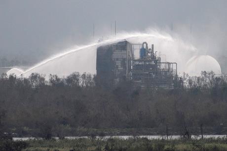 Firefighters douse the exterior of a chemical plant with water after a fire following a storm