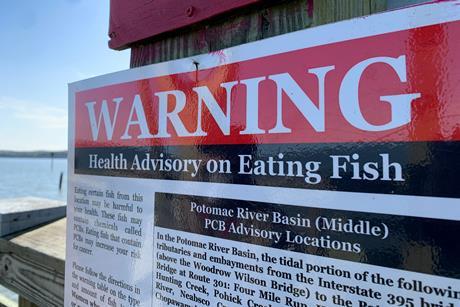 A sign by a lake warning against eating fish from the lake due to PCB which is harmful to human health