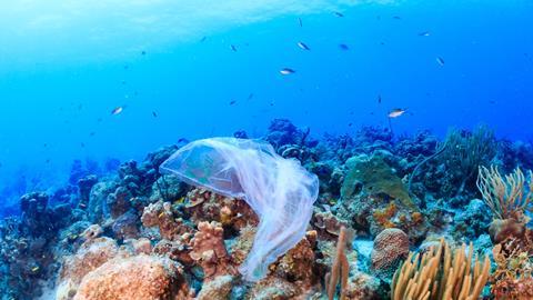 Plastic pollution: a discarded plastic rubbish bags floats on a tropical coral reef presenting a hazard to marine life