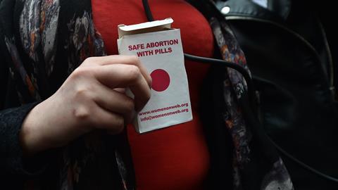 An image showing the hands of a woman holding a packet that reads "Safe abortion with pills"