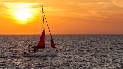 Yacht with red sails in sunset
