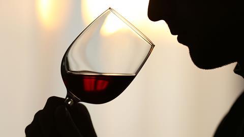 Silhouette man sniffing red wine