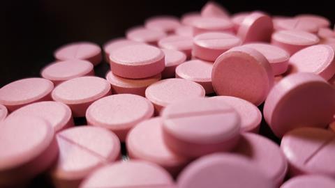 Pink nitroglycerine tablets scattered on a black background