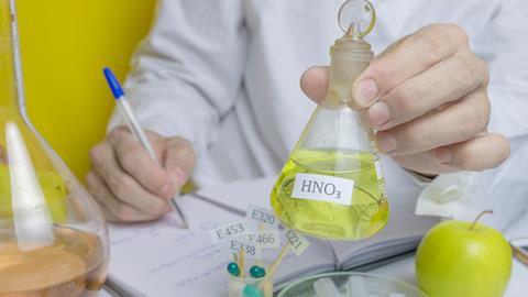 Lab technician holding up a beaker of nitric acid