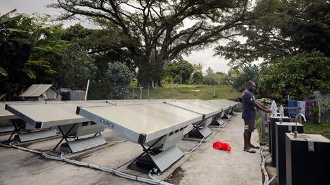 An image showing a man collecting water produced from a solar powered pilot project
