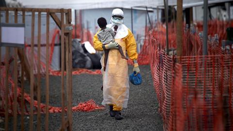 A Doctors Without Borders (MSF), health worker in protective clothing carries a child suspected of having Ebola