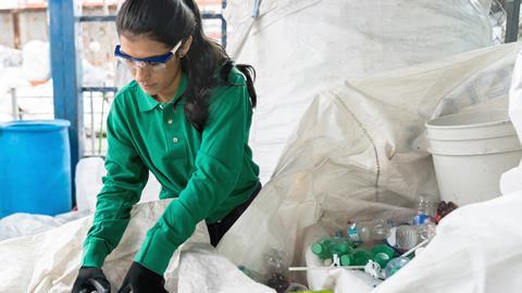 An image showing a woman sorting plastic recycling