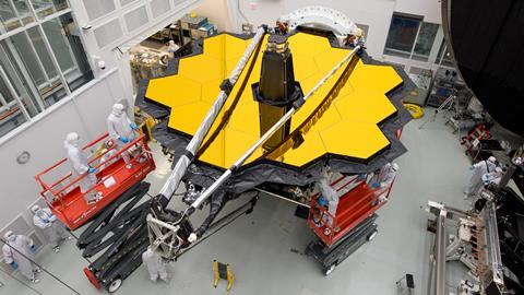An image showing workers next to the James Webb Space Telescope