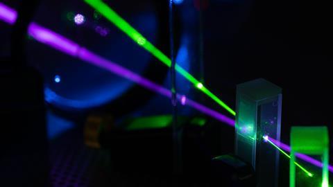 A photograph of green and blue lasers on optical table in physics laboratory