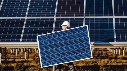 A photo of a worker carrying a solar panel