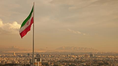 The Iranian flag flying above the Tehran skyline.