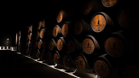 A row of barrels of port, stacked four high, recede into the distance