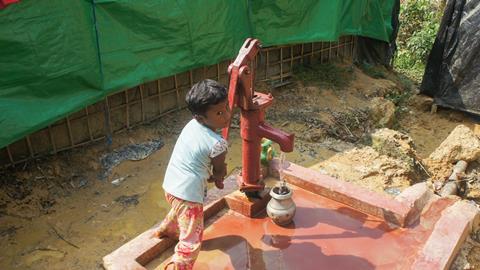 An image showing a small girl collecting water from tube well in Bangladesh