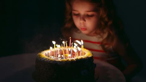 A picture of a little girl blowing candles on her birthday cake