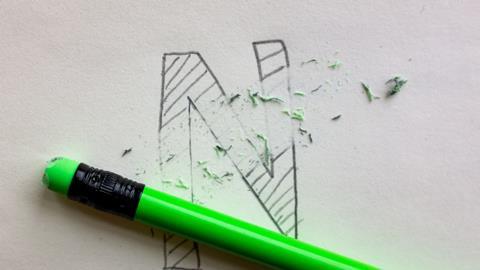 An image showing the letter N written in pencil being deleted with the eraser at the top of a neon green pencil