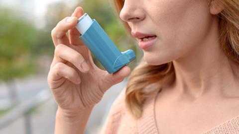 An image showing a woman using an inhaler