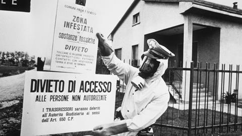 A black and white image of a policeman in Seveso, Italy pinning up warning signs written in Italian warning of chemical contamination of the area