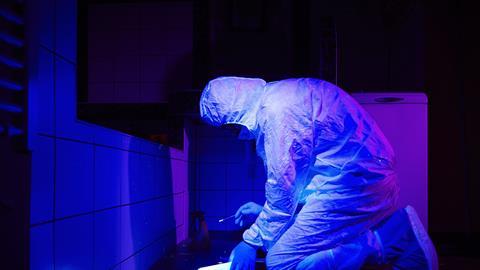 Technician collecting DNA evidence on place of crime under UV black light 