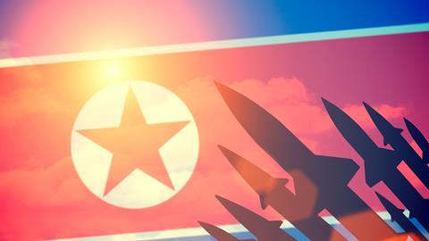 Rocket silhouettes against a background of the flag of North Korea