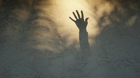 An image showing a shadow of a hand asking for help